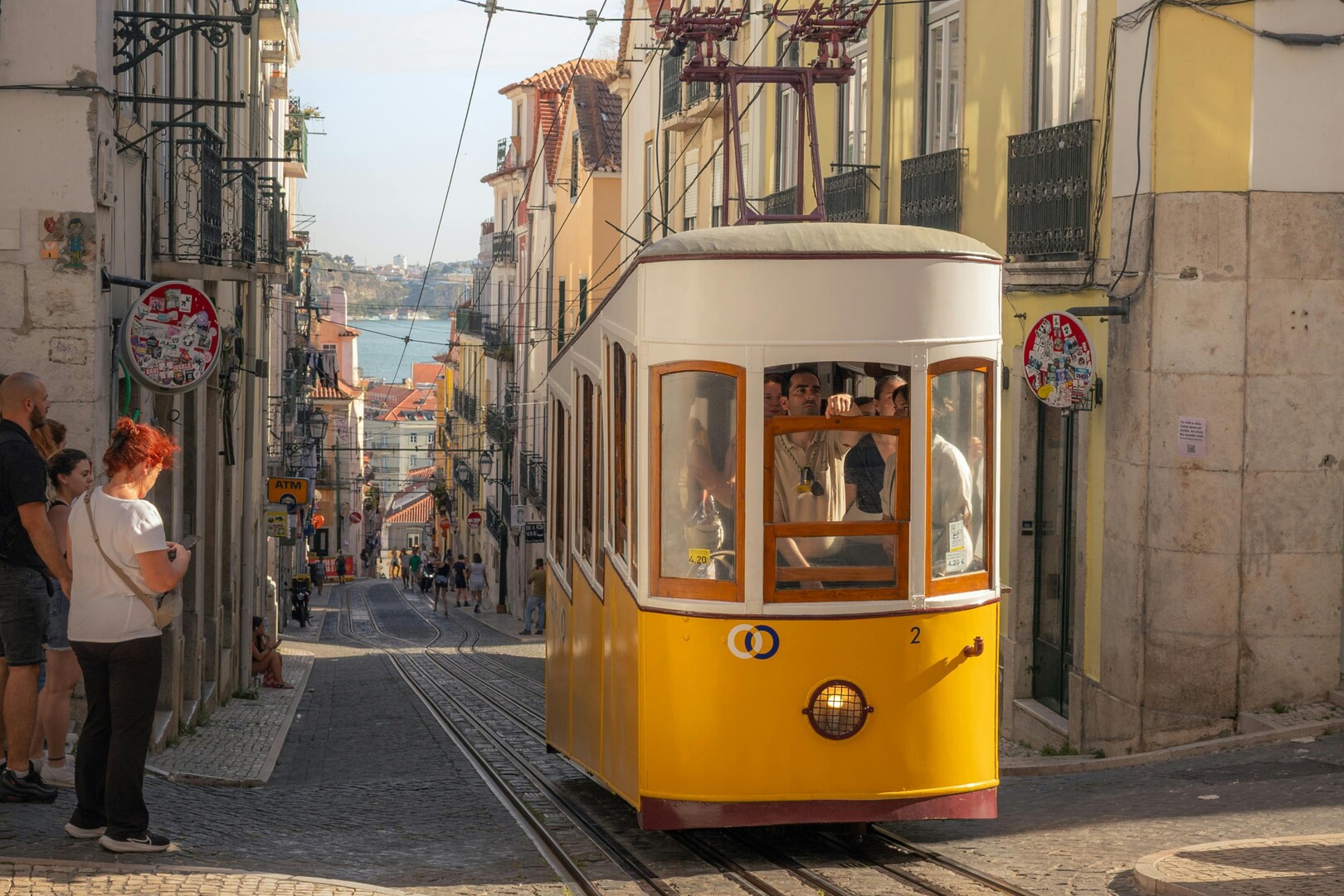 yellow tram passing through Alfama on cobbled street in spring