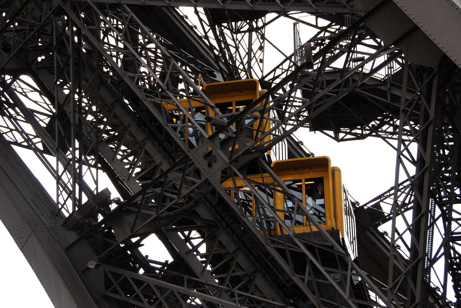 Glass elevator rising along the Eiffel Tower with Paris below