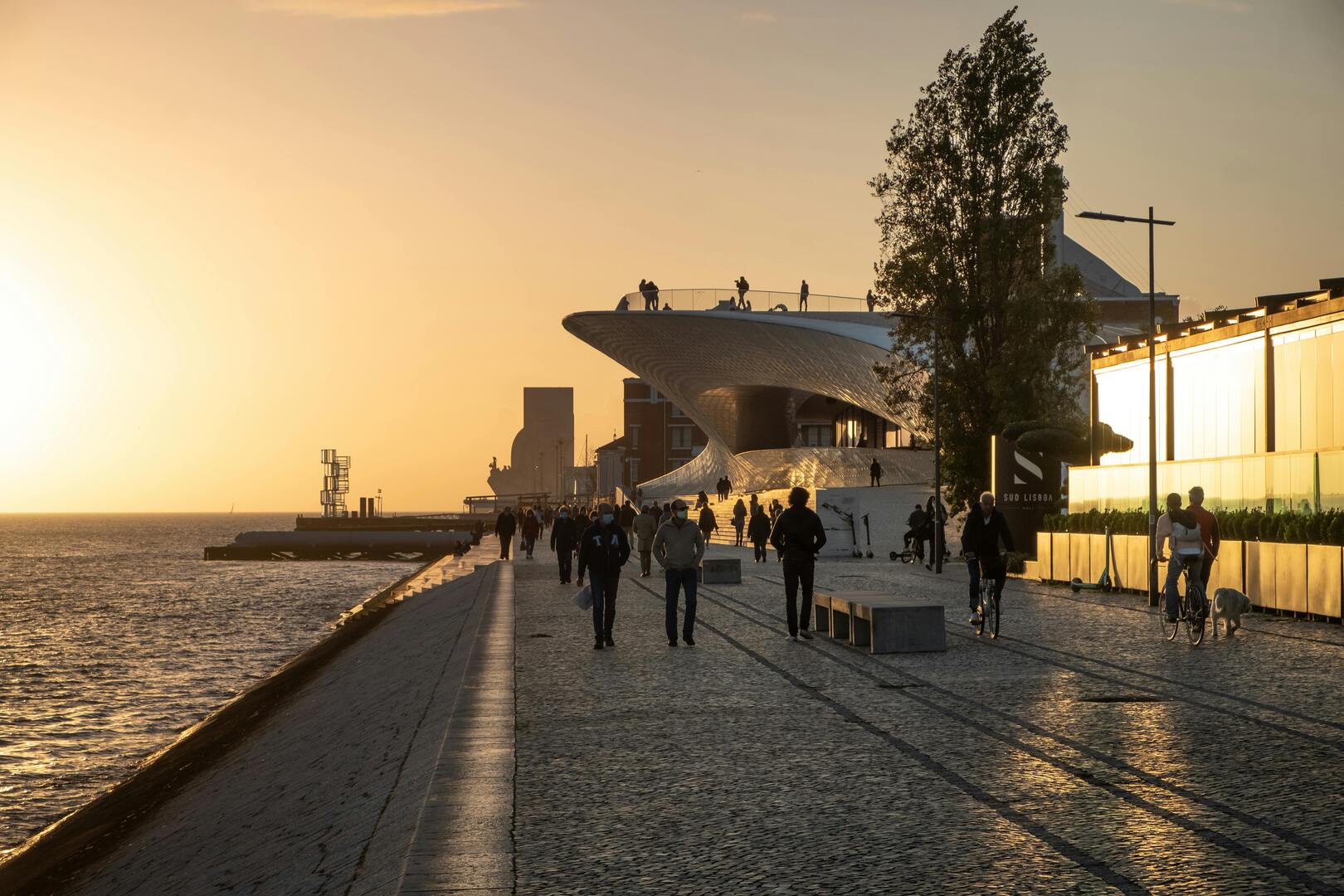 April light over Lisbon riverfront promenade with people walking