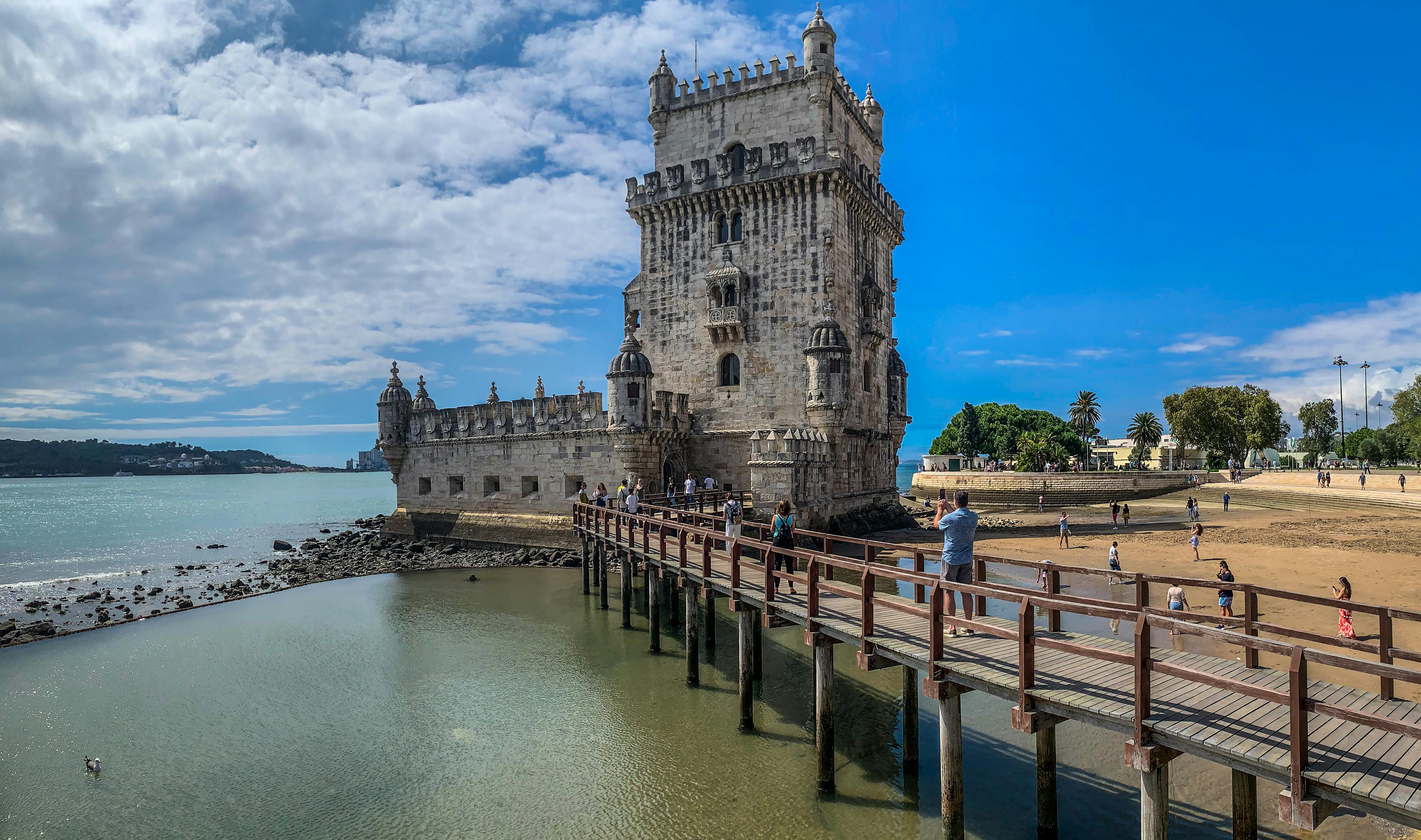 Spring light over Lisbon's Belem waterfront with people walking along the Tagus River
