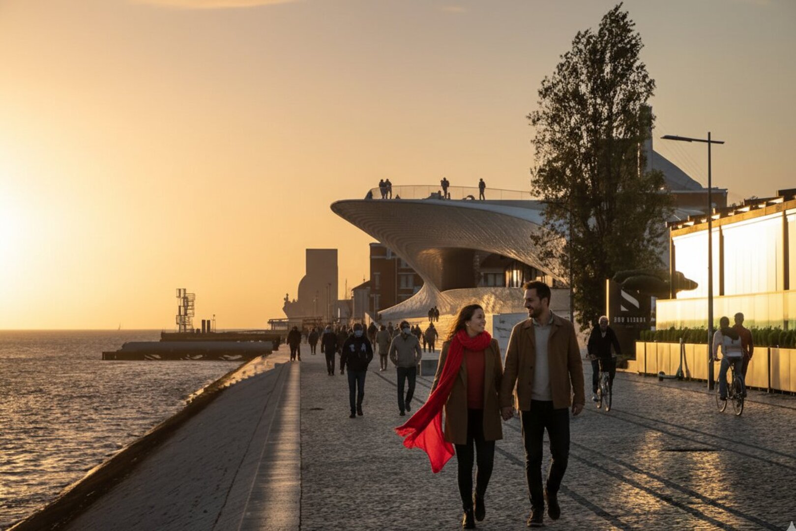 Couple walking along the Tagus riverfront at sunset near MAAT