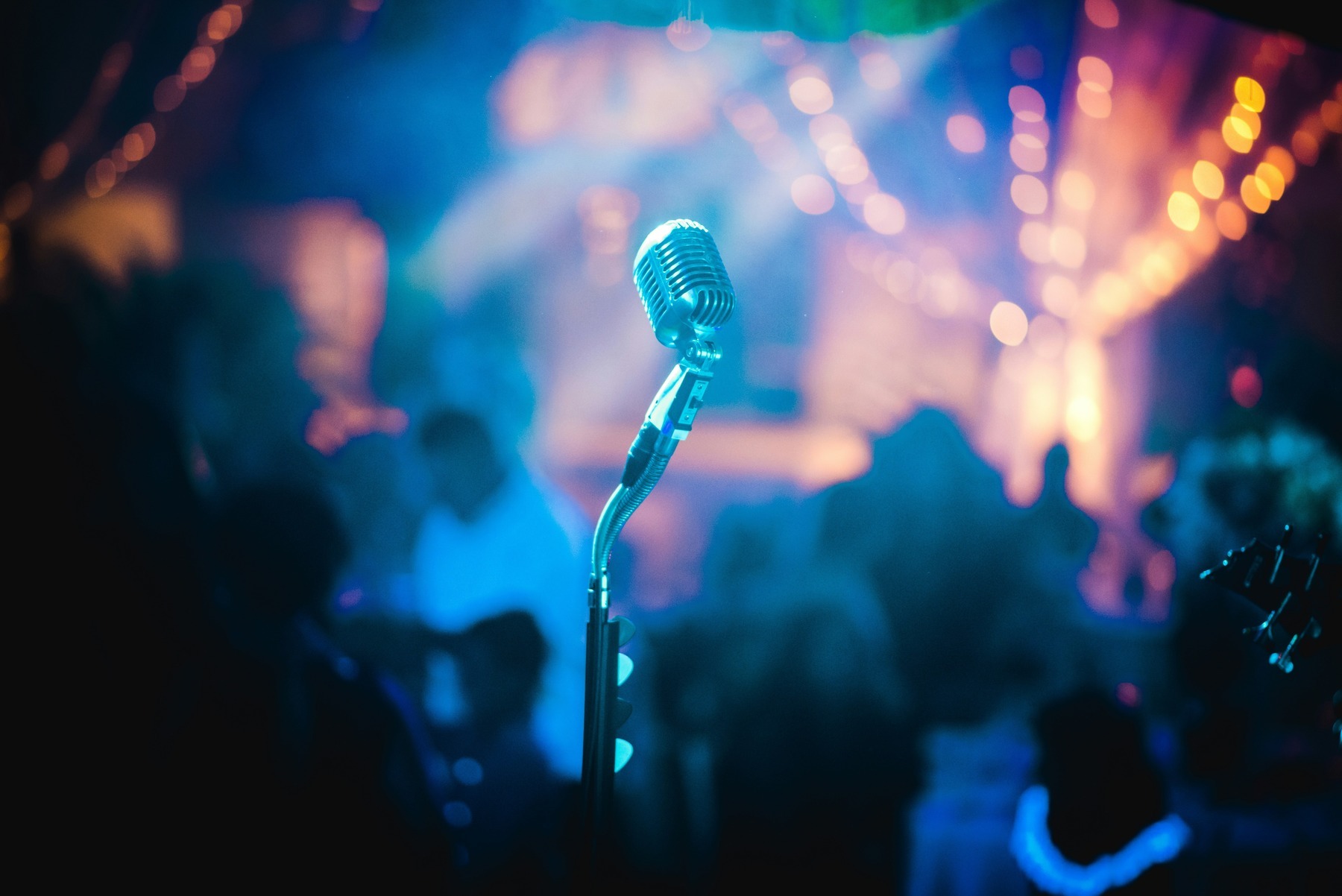 A vintage microphone on a festival stage lit by colourful lights at night
