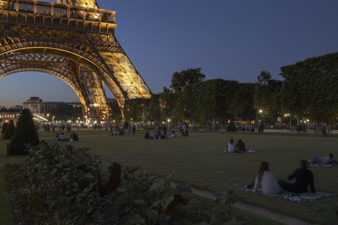 People walking and picnicking on the Champ de Mars in front of the Eiffel Tower