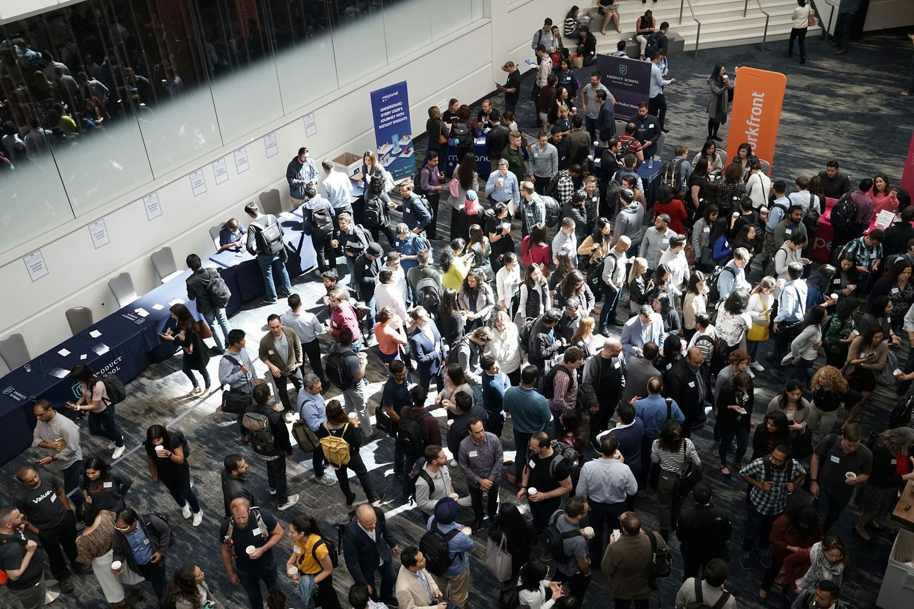 Conference attendees networking between exhibitor booths in a bright convention hall