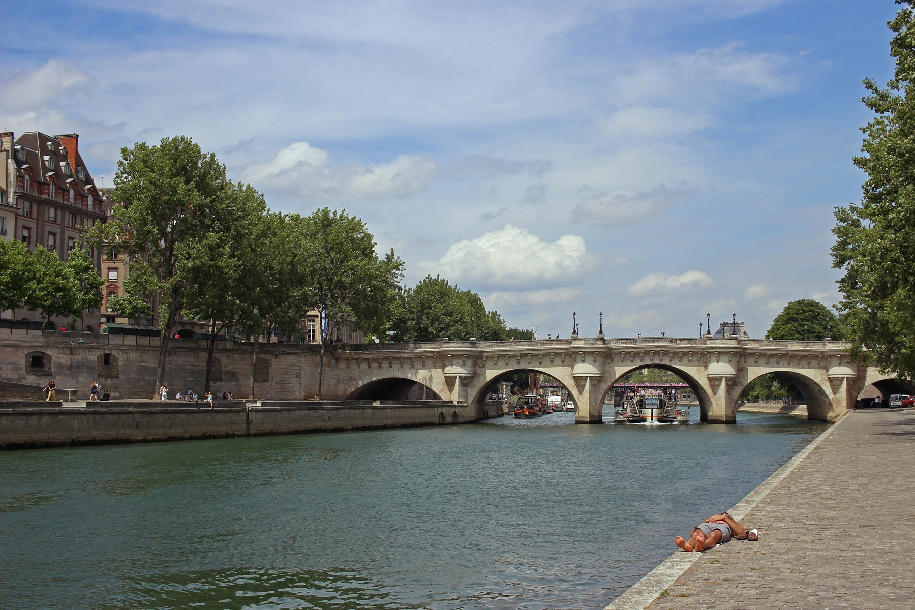 People relaxing on the Seine quayside beside the Pont Neuf during Paris Plages