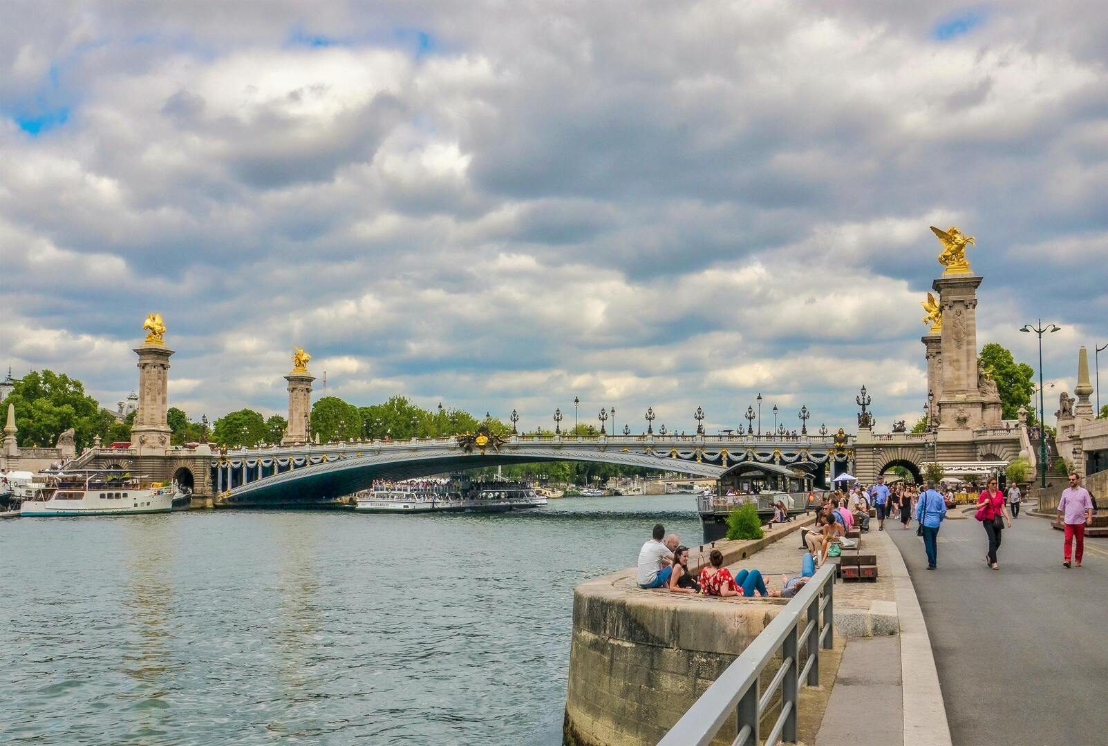 Seine riverbanks with pedestrians crossing a historic bridge in Paris