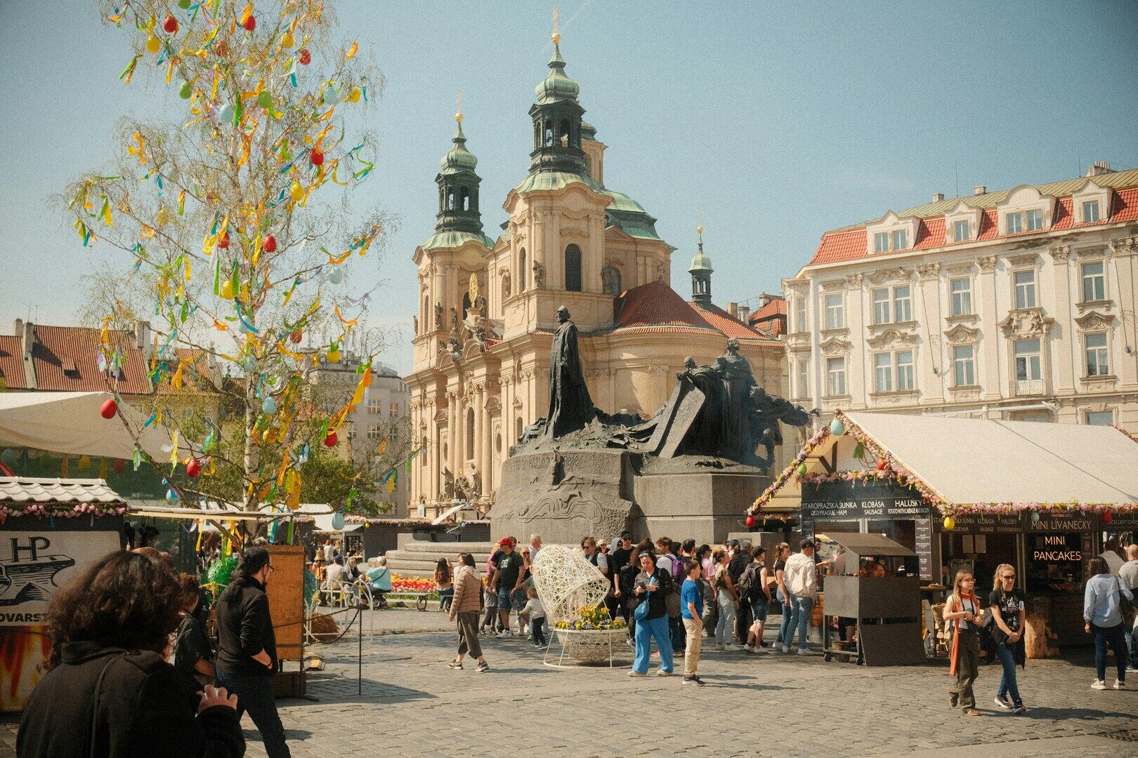 Spring market stalls in Prague Old Town Square beneath historic towers