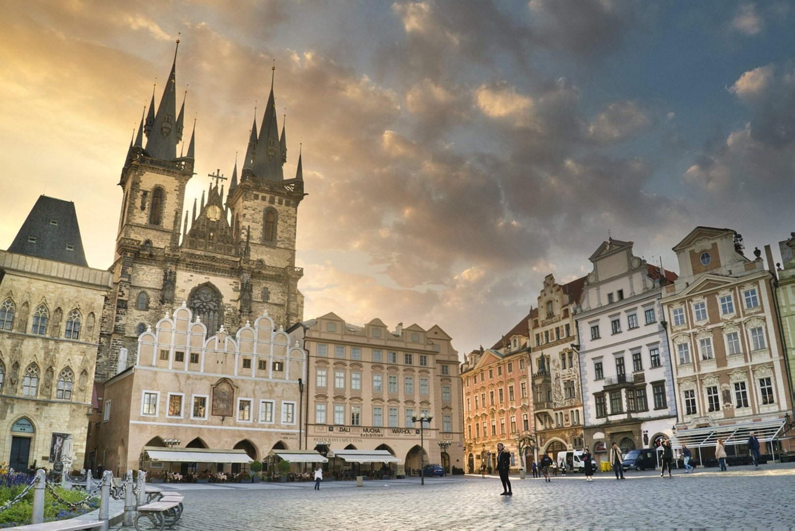 Prague Old Town Square on a warm May morning with open-air market stalls and the Astronomical Clock tower