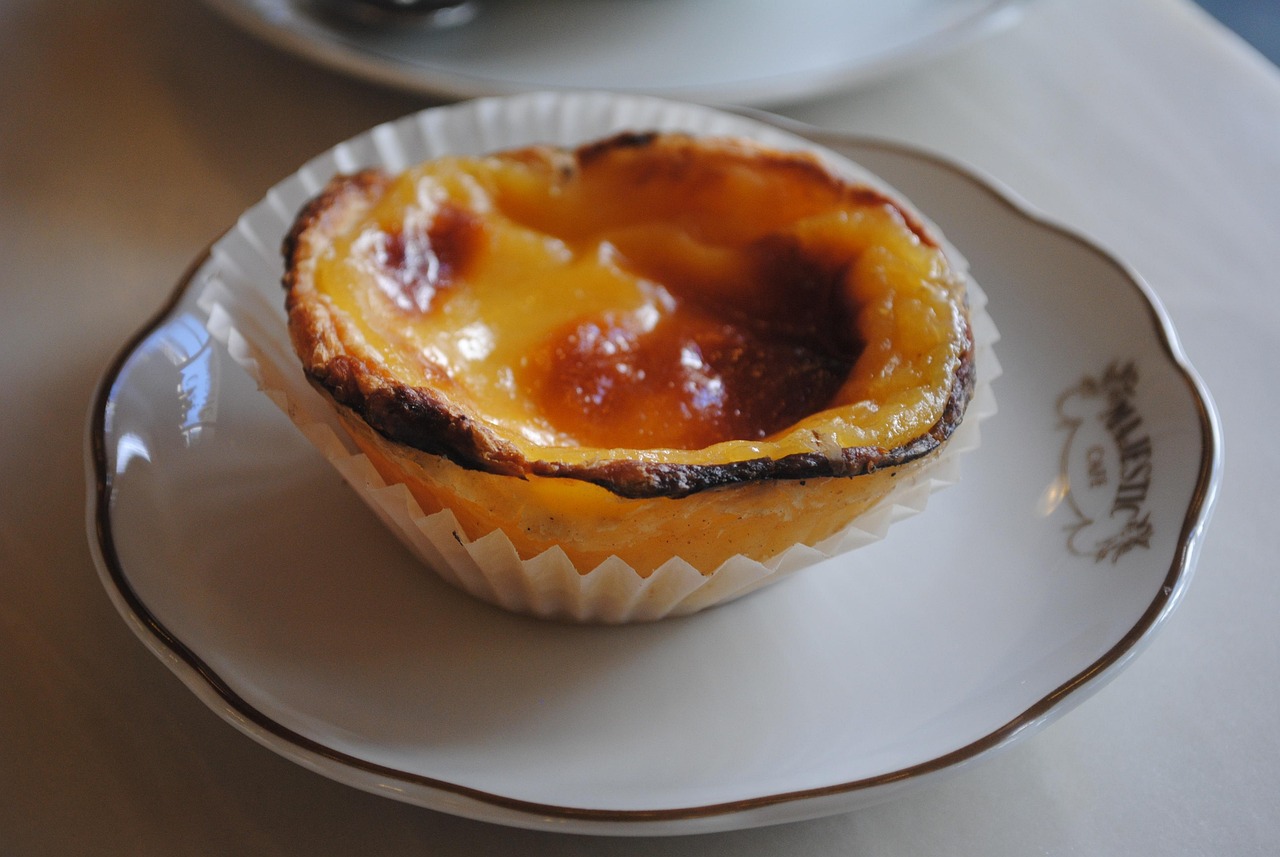 A single pastel de nata dusted with cinnamon on a café plate