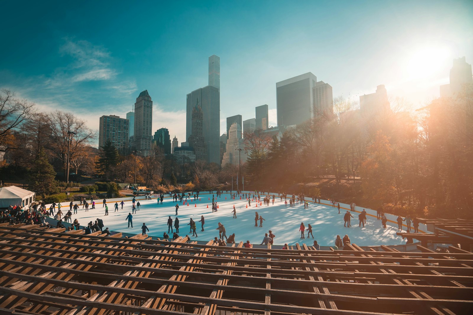 Skaters at an outdoor ice rink in Central Park with the Manhattan skyline behind